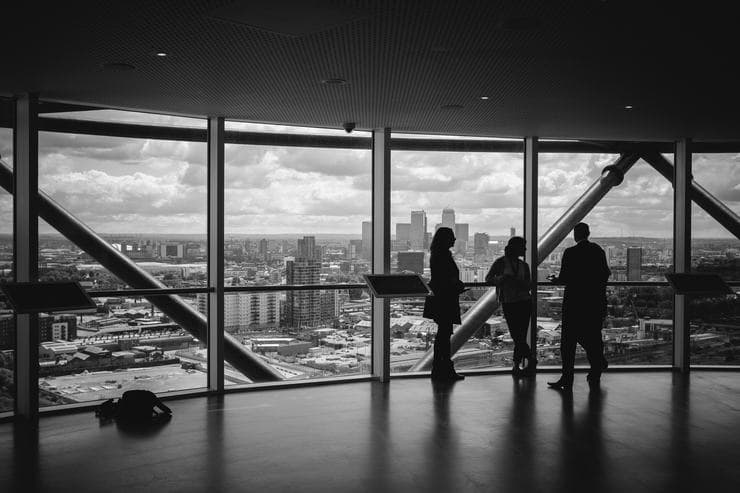 People beside office windows overlooking a city